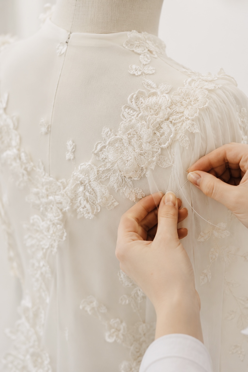 Floral lace applique being hand stitched onto a couture bodice