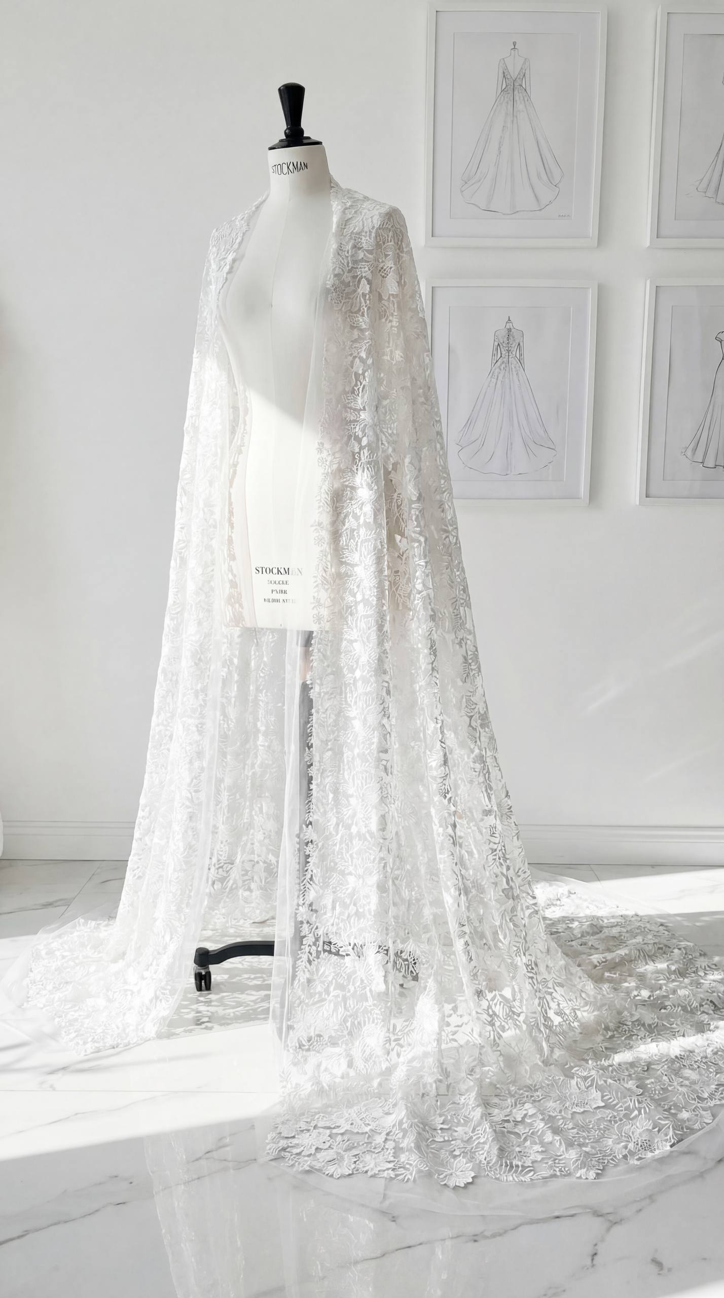 Draped lace atelier piece shown on a dress form beside framed sketches